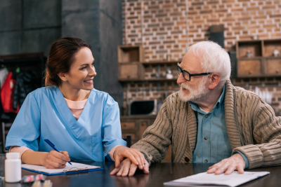 Nurse writing down senior patient medical complaints and holding his hand